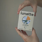 Auspacken der Lunette-Menstruationstasse: die Verpackung, der Leinenbeutel und die Tasse in der Hand